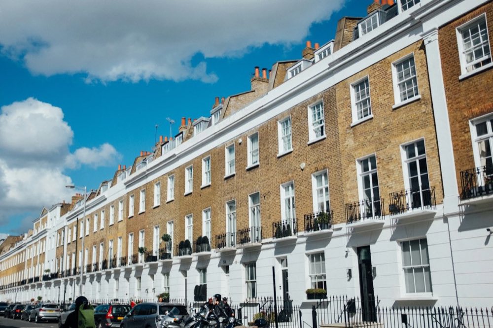 A row of London terraced houses under a blue sky